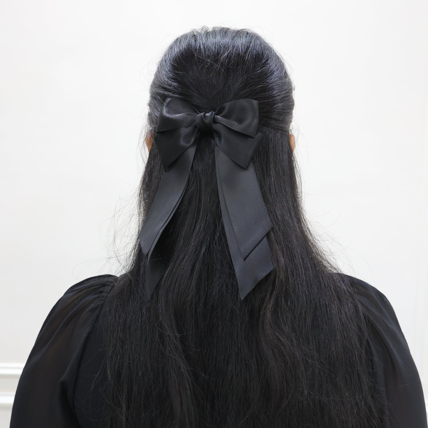 Model wearing Tesral Cascade Black Satin Bow, styled in a sleek half up and half down, showcasing polished finish and versatile elegance.