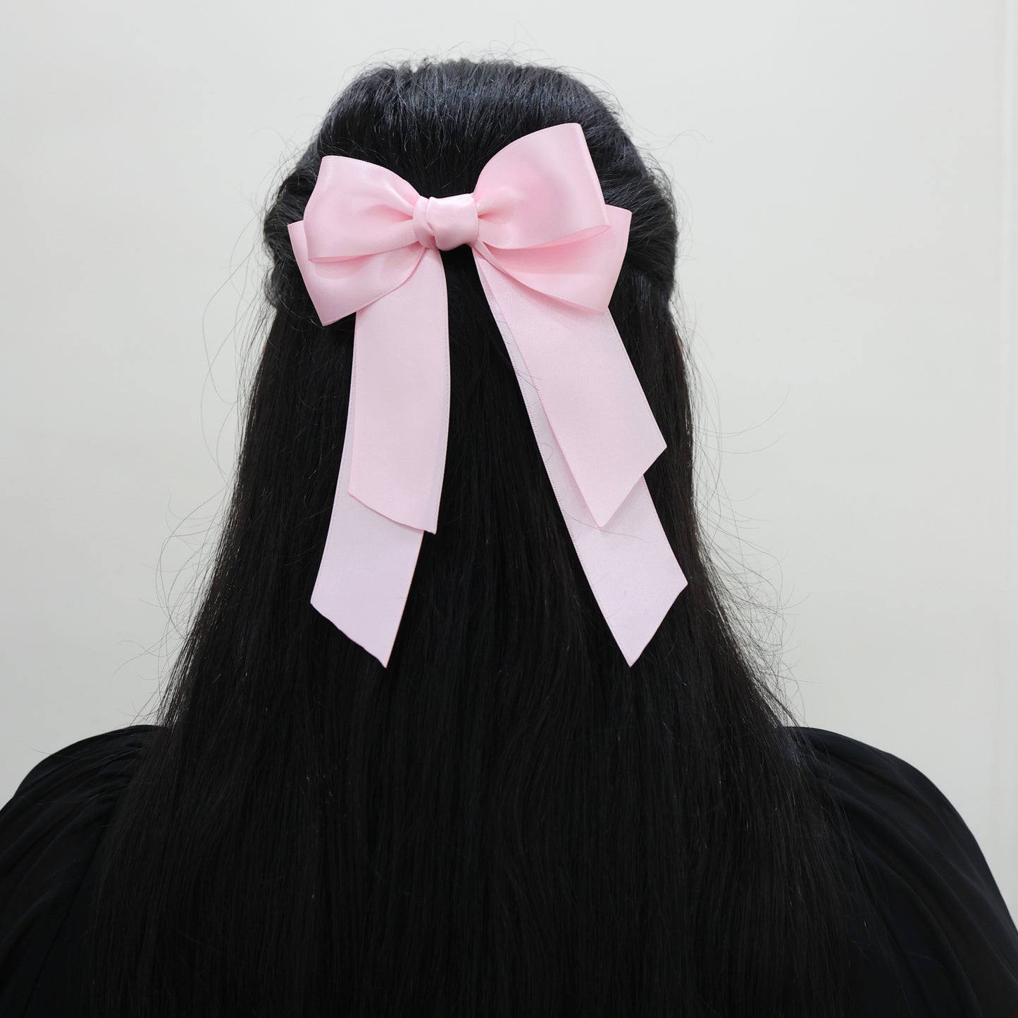 Model wearing Tesral Cascade Pearl Pink Bow, showing gentle charm and elegant drape of the satin tails in hair.