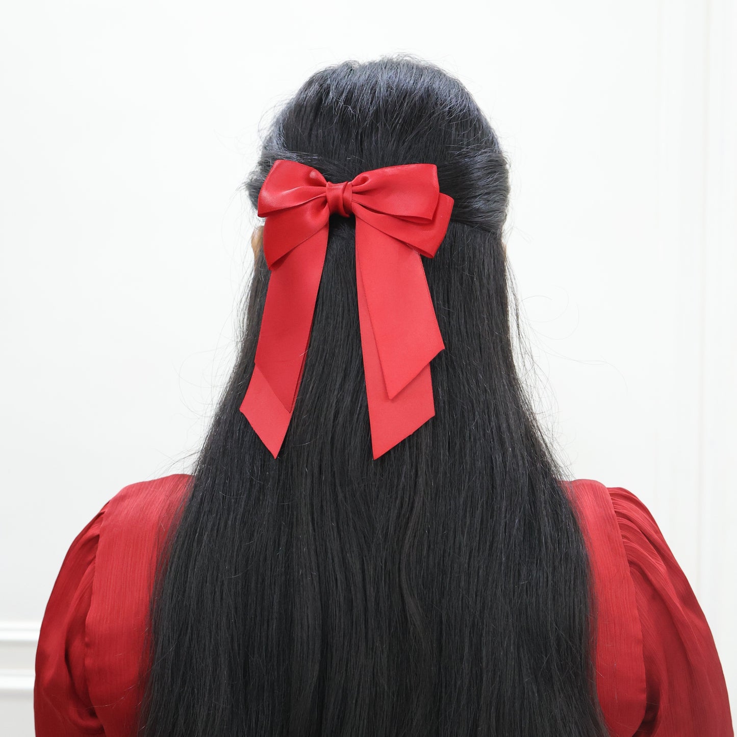 Model wearing Tesral Cascade Scarlet Red Bow, displaying long cascading tails and elegant silhouette for festive occasions.