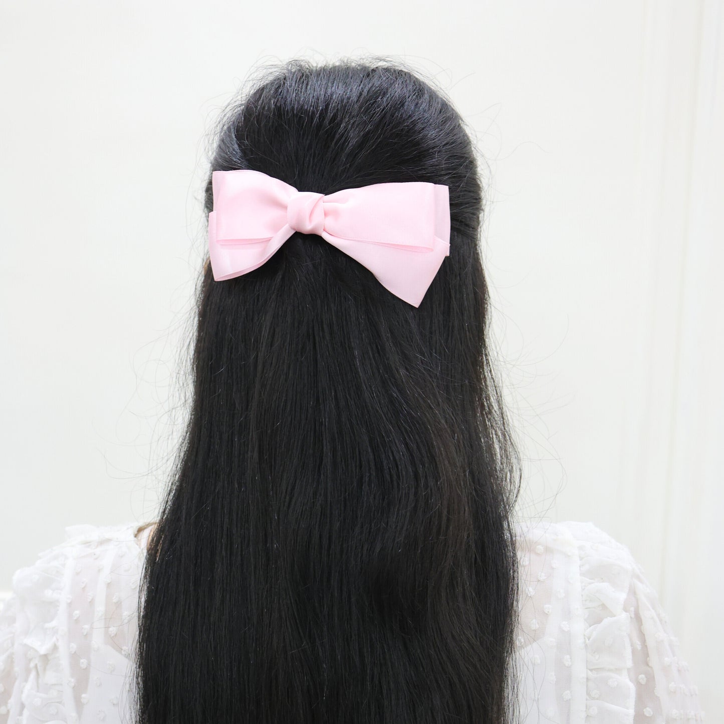 Model wearing Tesral Diana Bow in Pearly Pink, showcasing joyful charm and polished silhouette as a standout hair accessory.