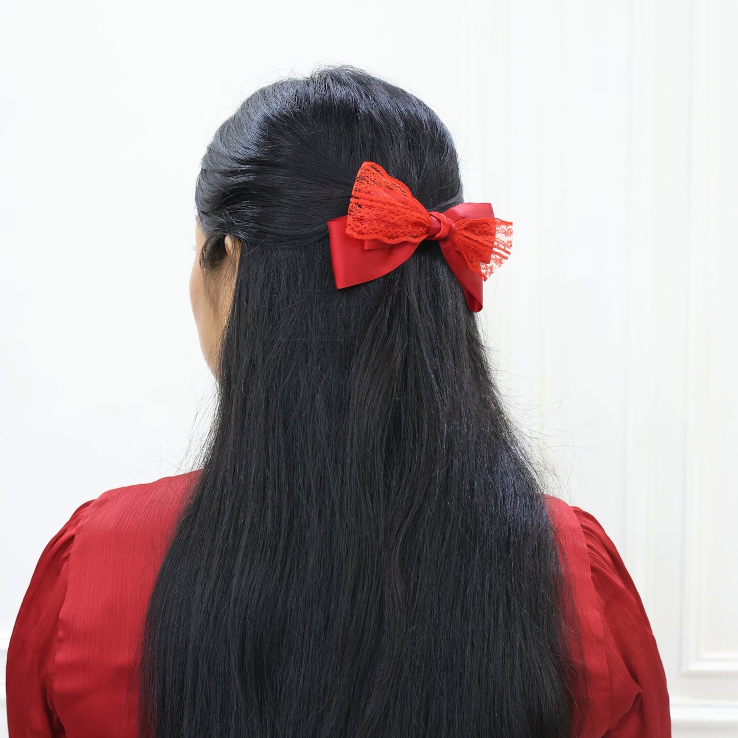 Woman wearing Glory Bow in Red – statement hair piece for festive styling by Tesral Accessories