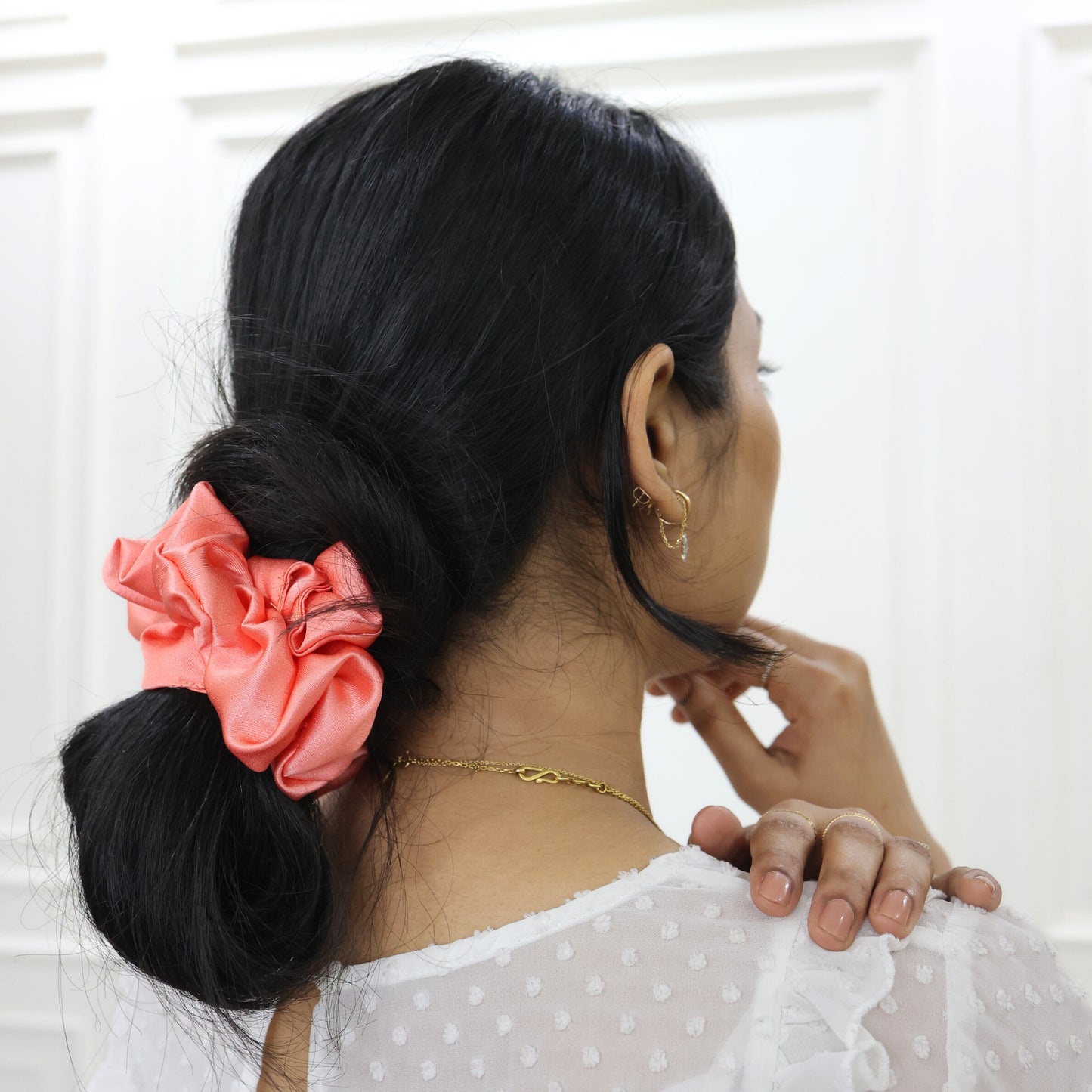 Woman styling hair with Tesral Peach Whirl Scrunchie, soft hold without creases, ideal for all-day comfort.