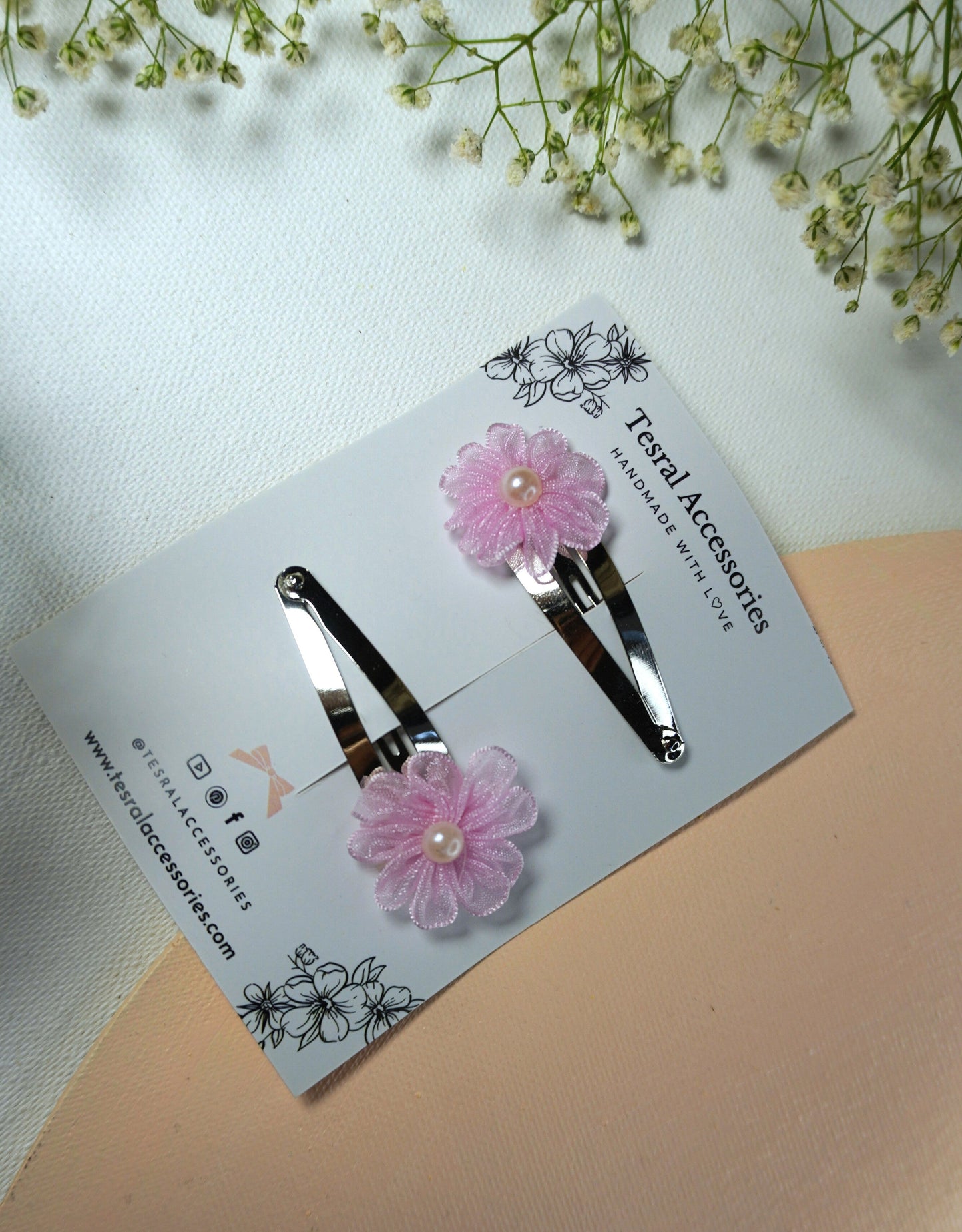 Close-up of pink layered fabric flower hair clip with pearl center
