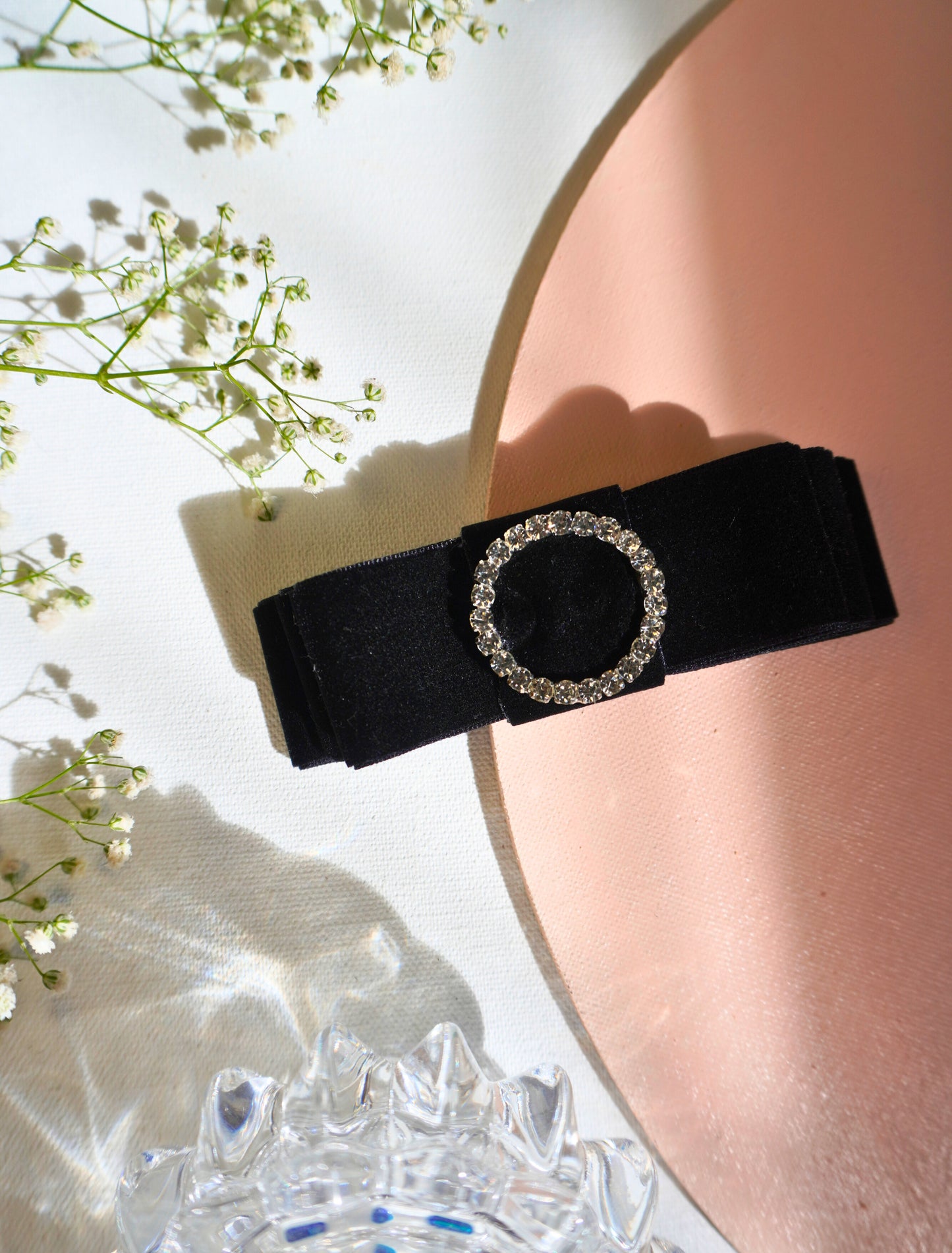 A close-up of "The Empress" black velvet hair bow, highlighting the intricate texture of the luxurious black velvet and the brilliant sparkle of the round diamond centerpiece. The image focuses on the triple-bow structure, showing the detailed craftsmanship and elegant folds of the fabric.