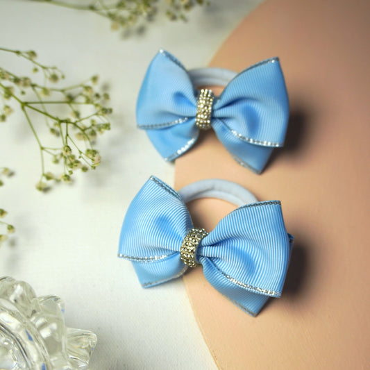 Close-up of light blue grosgrain hair bow with silver-edged detail and rhinestone centerpiece