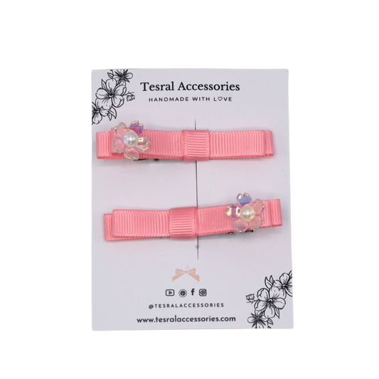Two pink hair clips with floral accents set on a alligator clip 