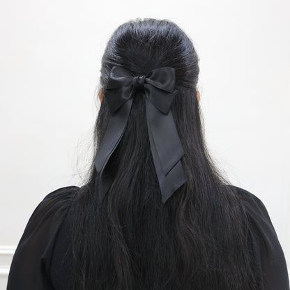 Model wearing Tesral Cascade Black Satin Bow, styled in a sleek half up and half down, showcasing polished finish and versatile elegance.