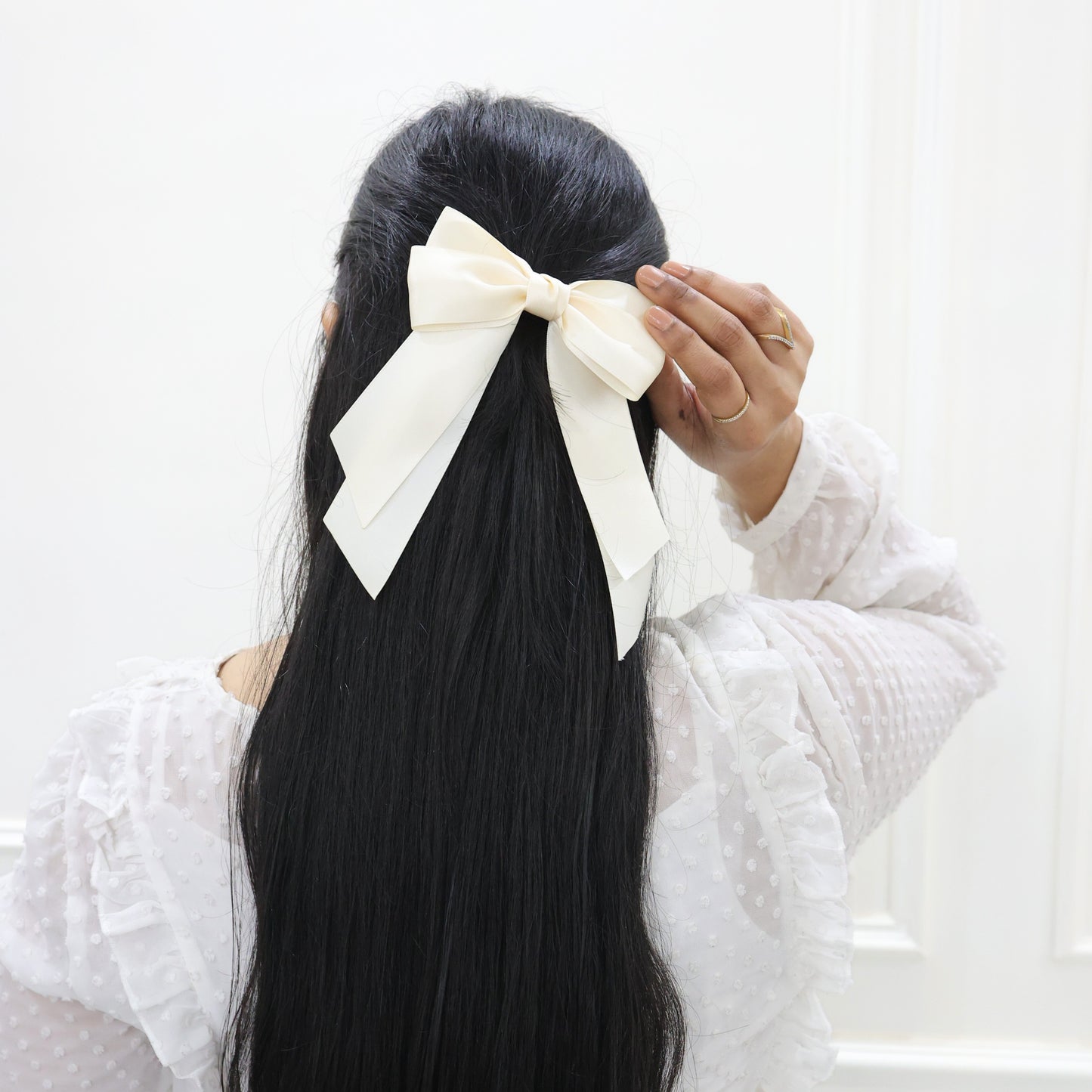 Model wearing Tesral Cascade Ivory Satin Bow, demonstrating its pure and pristine grace in a hairstyle, suitable for formal or casual outfits.