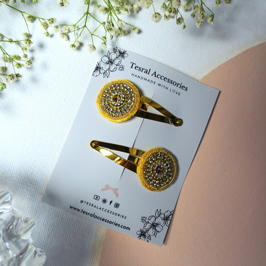 Close-up of embroidered golden hair clip with embedded rhinestones