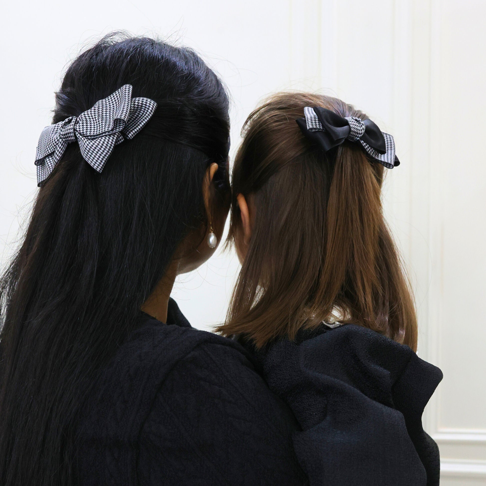 Woman wearing the Lady Houndstooth Hair Bow, styled in a half-up hairdo, showcasing the elegant black-and-white houndstooth pattern as a chic statement accessory.