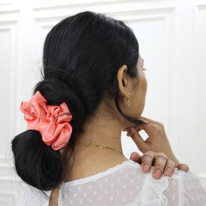 Woman styling hair with Tesral Peach Whirl Scrunchie, soft hold without creases, ideal for all-day comfort.
