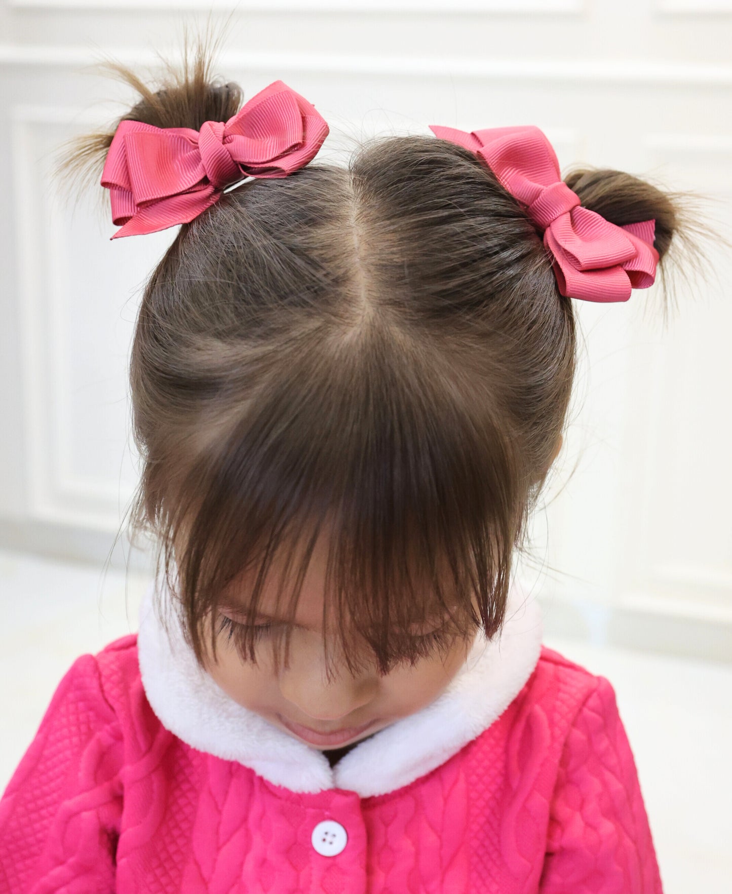 Child wearing Rosy Twirls colonial pink grosgrain hair bows on space buns– set of two alligator clip bows by Tesral Accessories