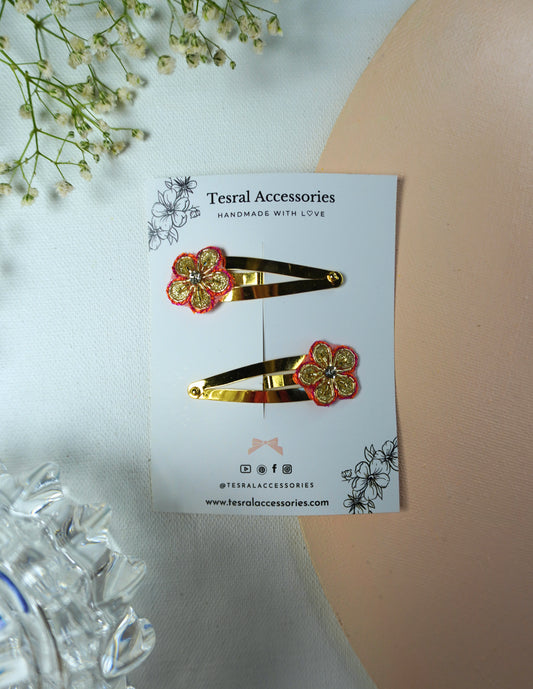 Close-up of gold tic-tac clip with red and gold floral applique for festivals