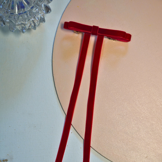 A sleek redvelvet ribbon bow designed with long cascading tail for an effortlessly elegant look. Minimal yet striking, this piece adds refined drama and modern femininity to evening wear, festive parties, and sophisticated everyday styling.